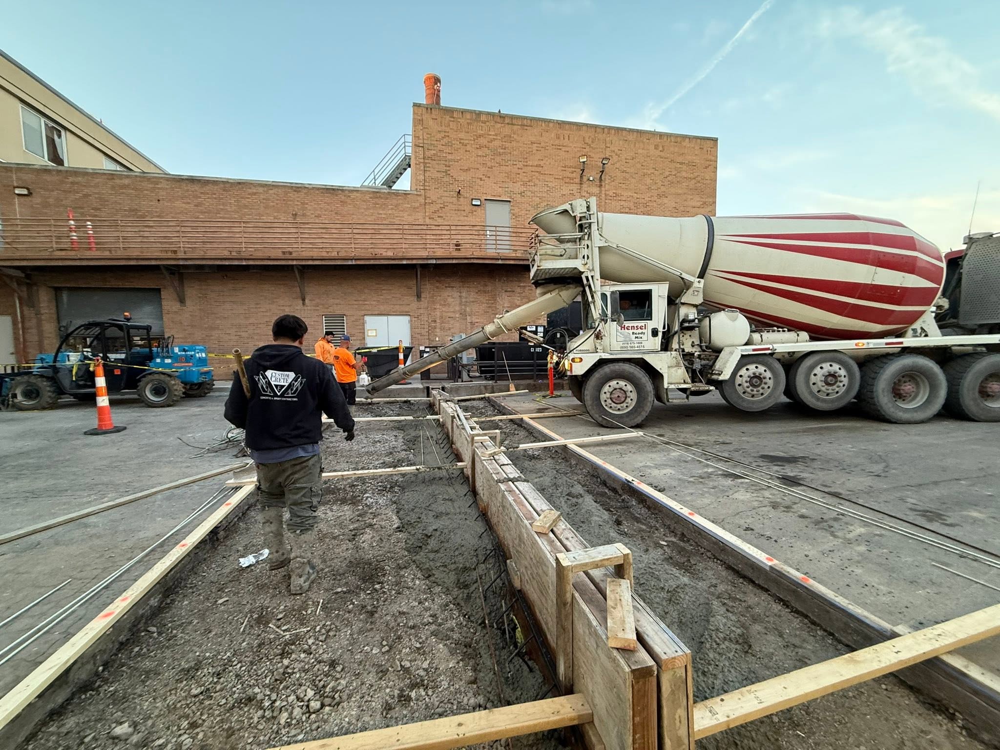 Custom Crete crew placing forms and rebar with a ready-mix truck at a commercial loading dock